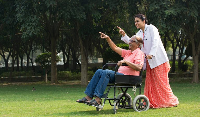 A doctor taking a patient for walk on wheelchair as a part of post-surgery care
