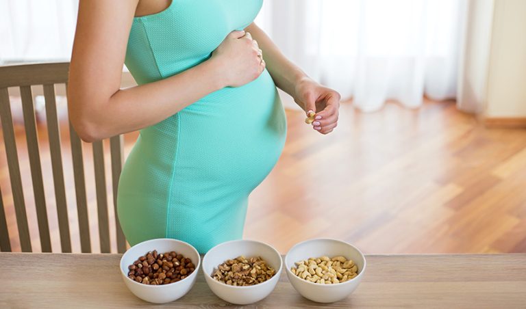 A pregnant woman snacking on protein-rich seeds and nuts